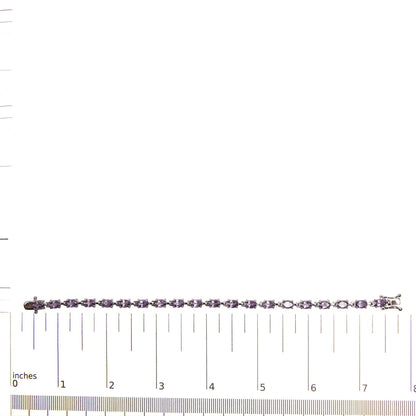 White metal bracelet with purple oval gemstones in 4-prong settings, laid flat on a ruler for size reference, shot from above.