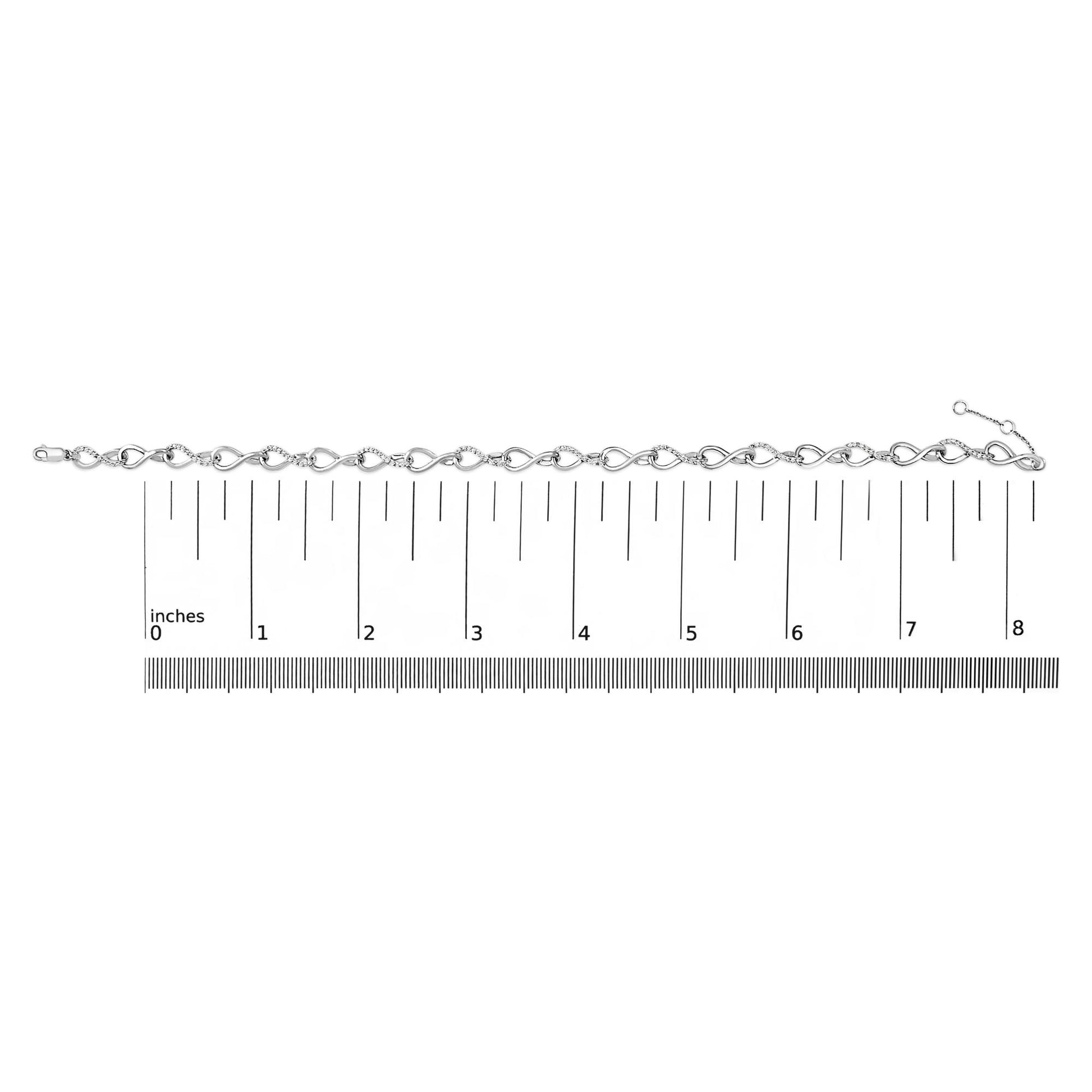 White metal bracelet with alternating plain and white gemstone-studded infinity-shaped links, shown on a scale from a top-down angle.