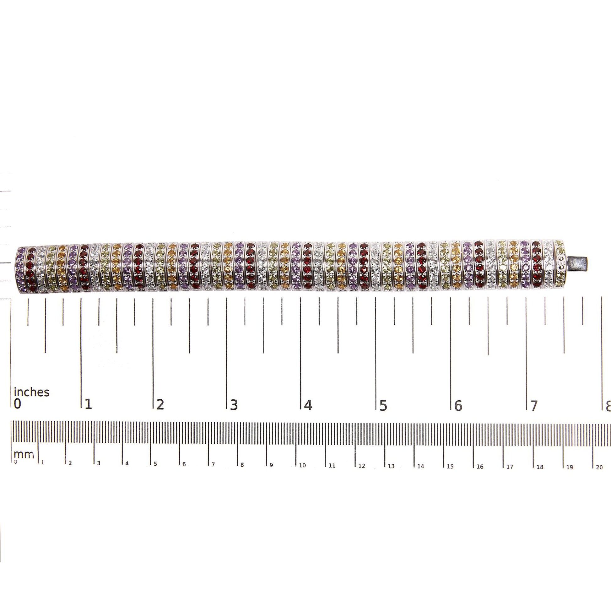 Top-down view of a white metal bracelet with multiple rows of round purple, blue, lemon, yellow, and red gemstones in shared prong settings, placed on a ruler for size reference.