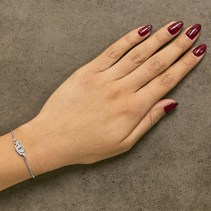 White metal bracelet with round white gemstones in a shared prong setting, shown worn on a model's wrist from a top angle.