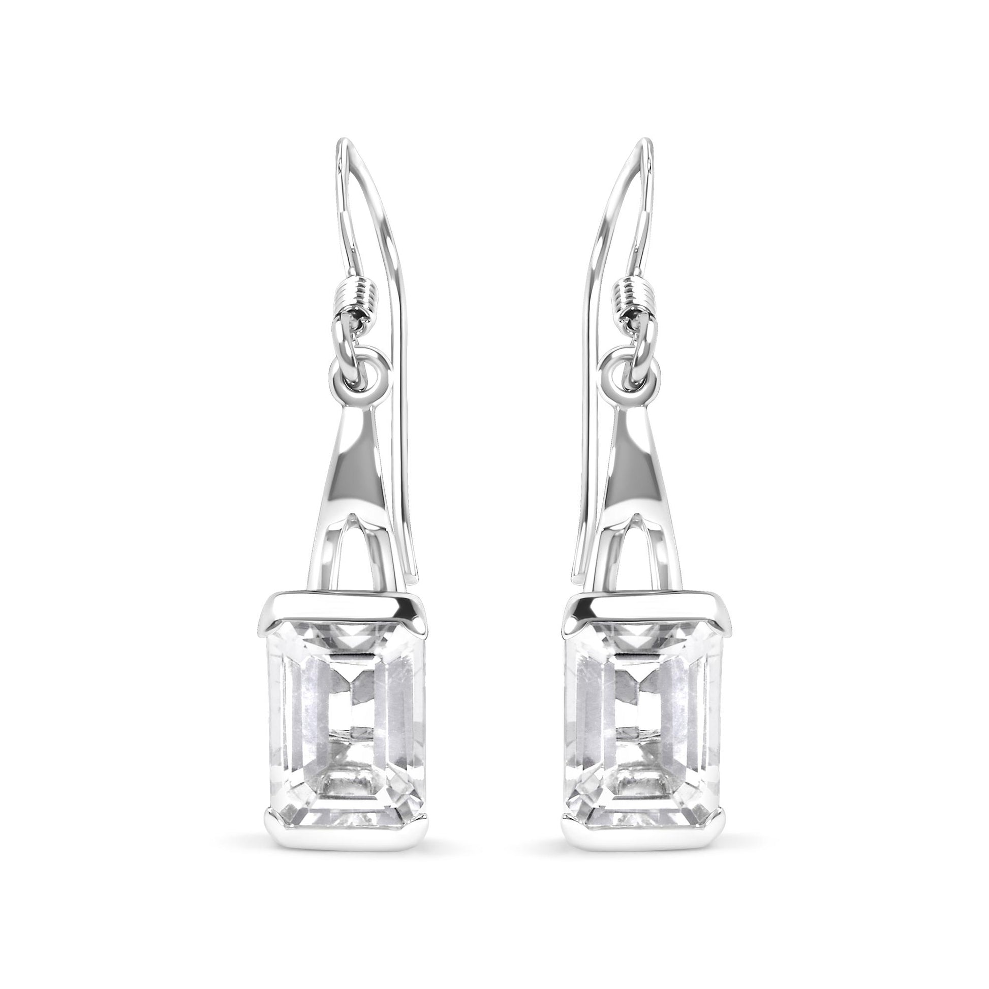 Front-facing image of white metal earrings with emerald-cut white gemstones in four-prong settings hanging from hooks.