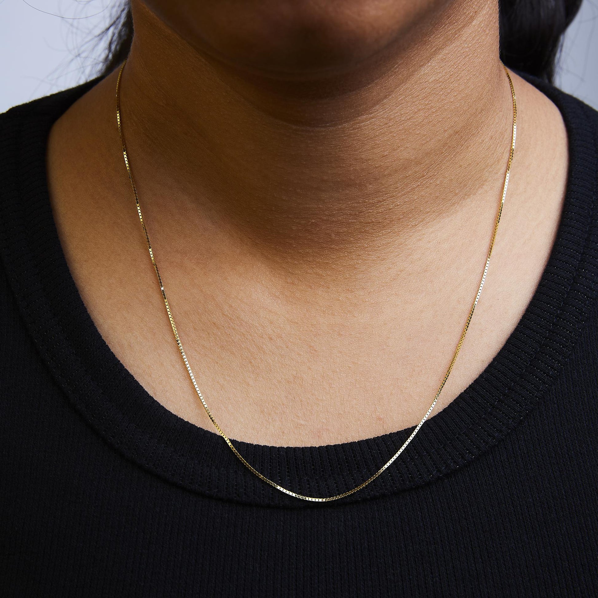 Yellow chain necklace shown worn on a model, front close-up view.