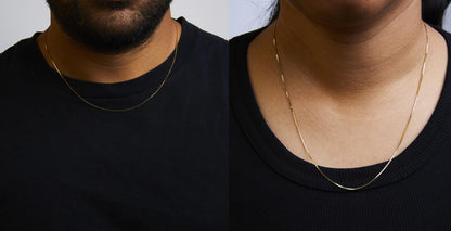 Two close-up angled views of a thin yellow chain necklace worn on models dressed in black tops.