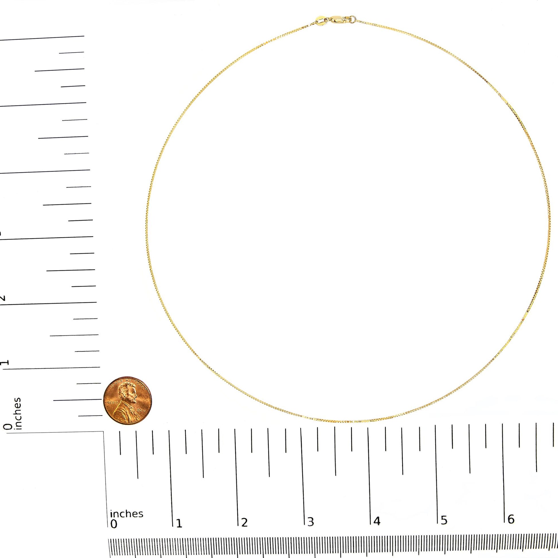 Top-down view of a thin yellow chain necklace with a clasp, displayed on a ruler for size reference.