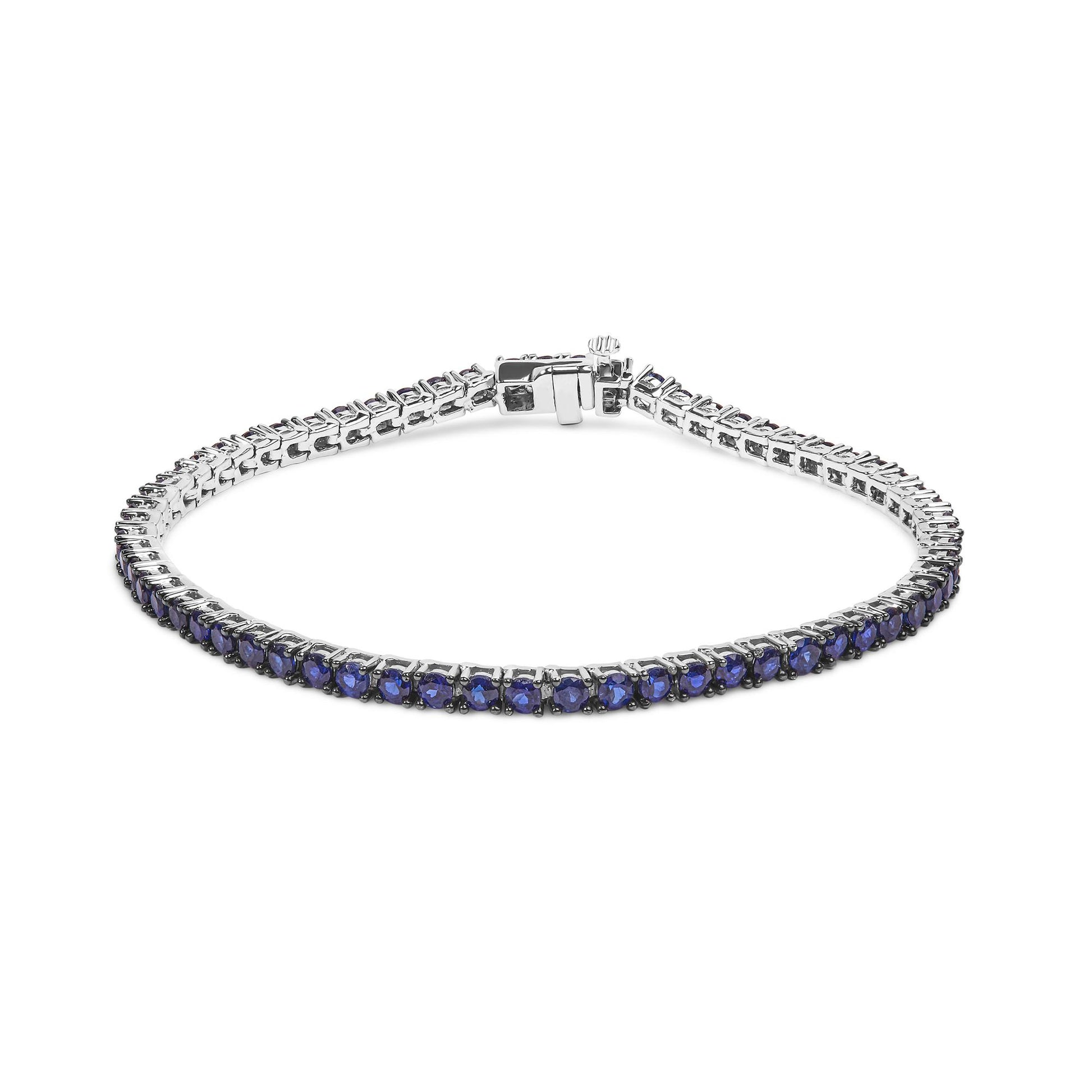 White metal bracelet with round blue gemstones in a shared prong setting, shown from a slightly elevated front angle.