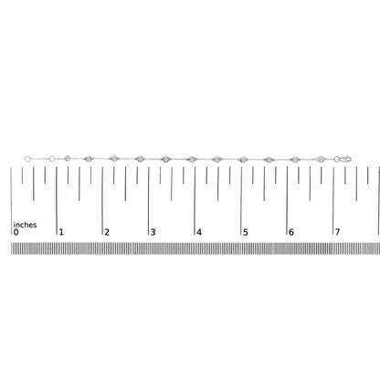 White metal bracelet with round bezel-set white gemstones, shown on a scale from a top-down angle.