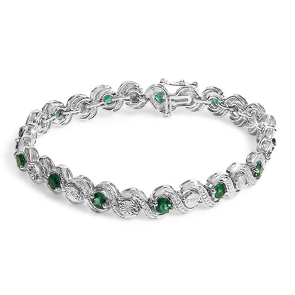 White bracelet with alternating round green gemstones set in prongs and round white gemstones in a miracle setting, shown from a top angle on a white background.