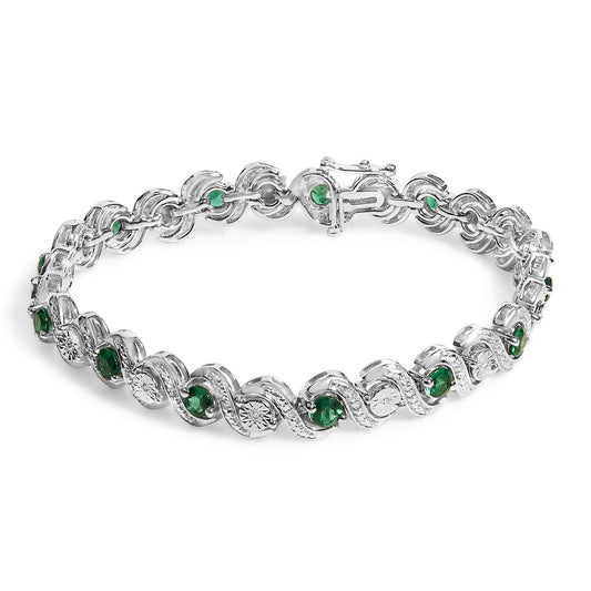 White bracelet with alternating round green gemstones set in prongs and round white gemstones in a miracle setting, shown from a top angle on a white background.