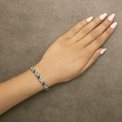 Bracelet with alternating round white and green gemstones in curved links, shown worn on a model's wrist, angled top-down.
