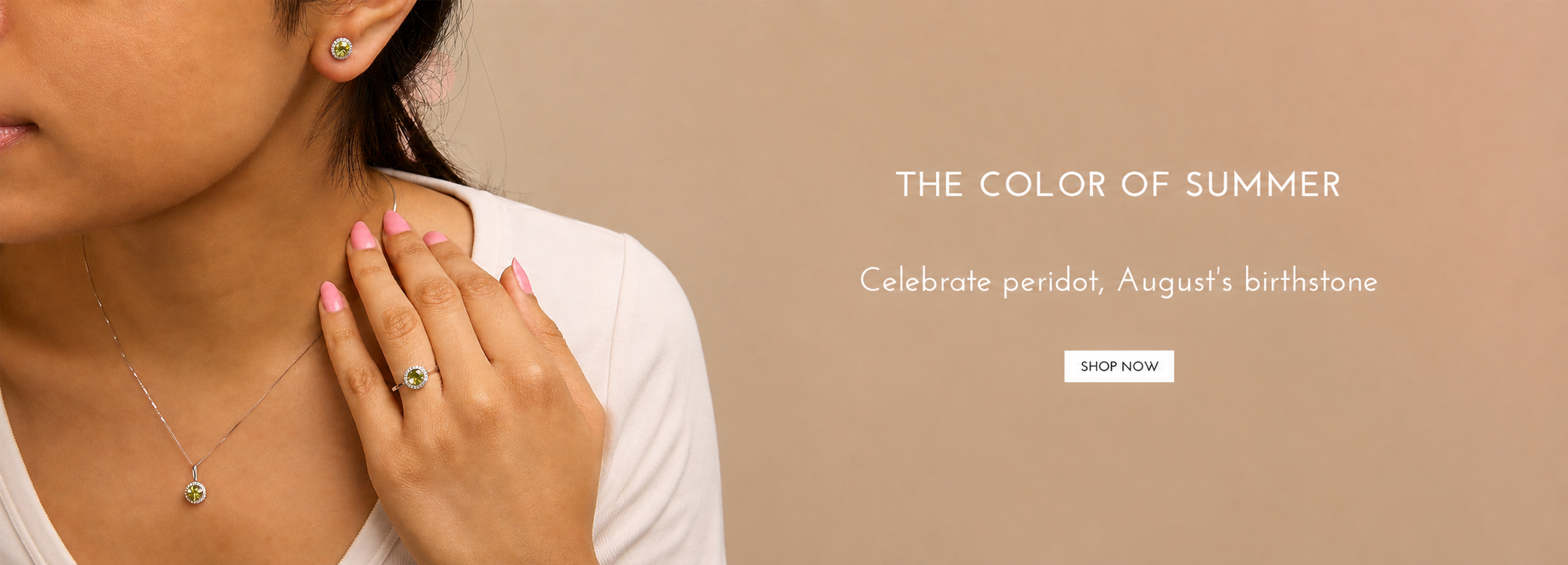 A close-up lifestyle shot of a woman wearing a delicate silver necklace with a small green pendant and a matching green stud earring, with her hand resting on her neck. The background is a solid warm beige with text reading 'THE COLOR OF SUMMER' and 'Celebrate peridot, August's birthstone' alongside a 'SHOP NOW' button.