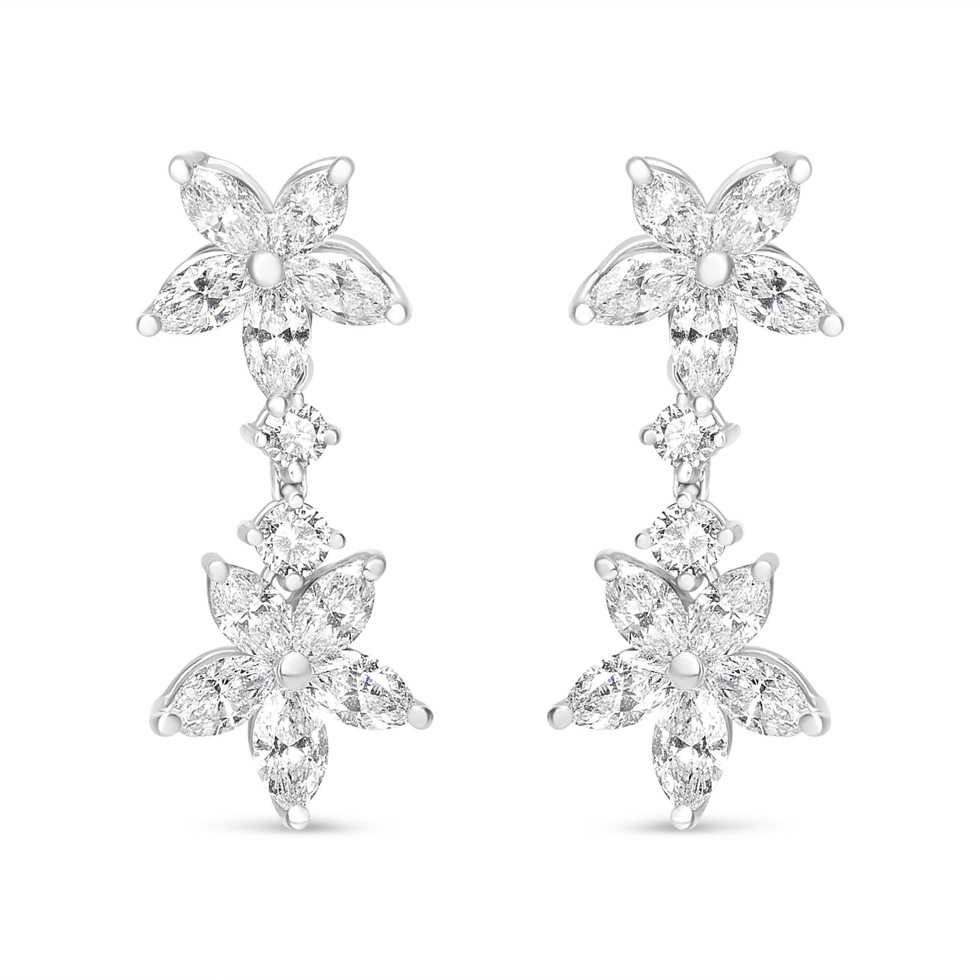 Front-facing shot of white metal earrings featuring two flower shapes composed of marquise-shaped white gemstones, connected by two round-shaped white gemstones in prong settings.