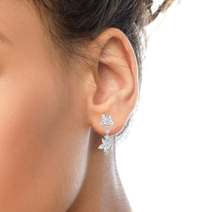 Close-up side view of a white metal earring on a model's ear featuring marquise-shaped and round white gemstones arranged in a floral design.