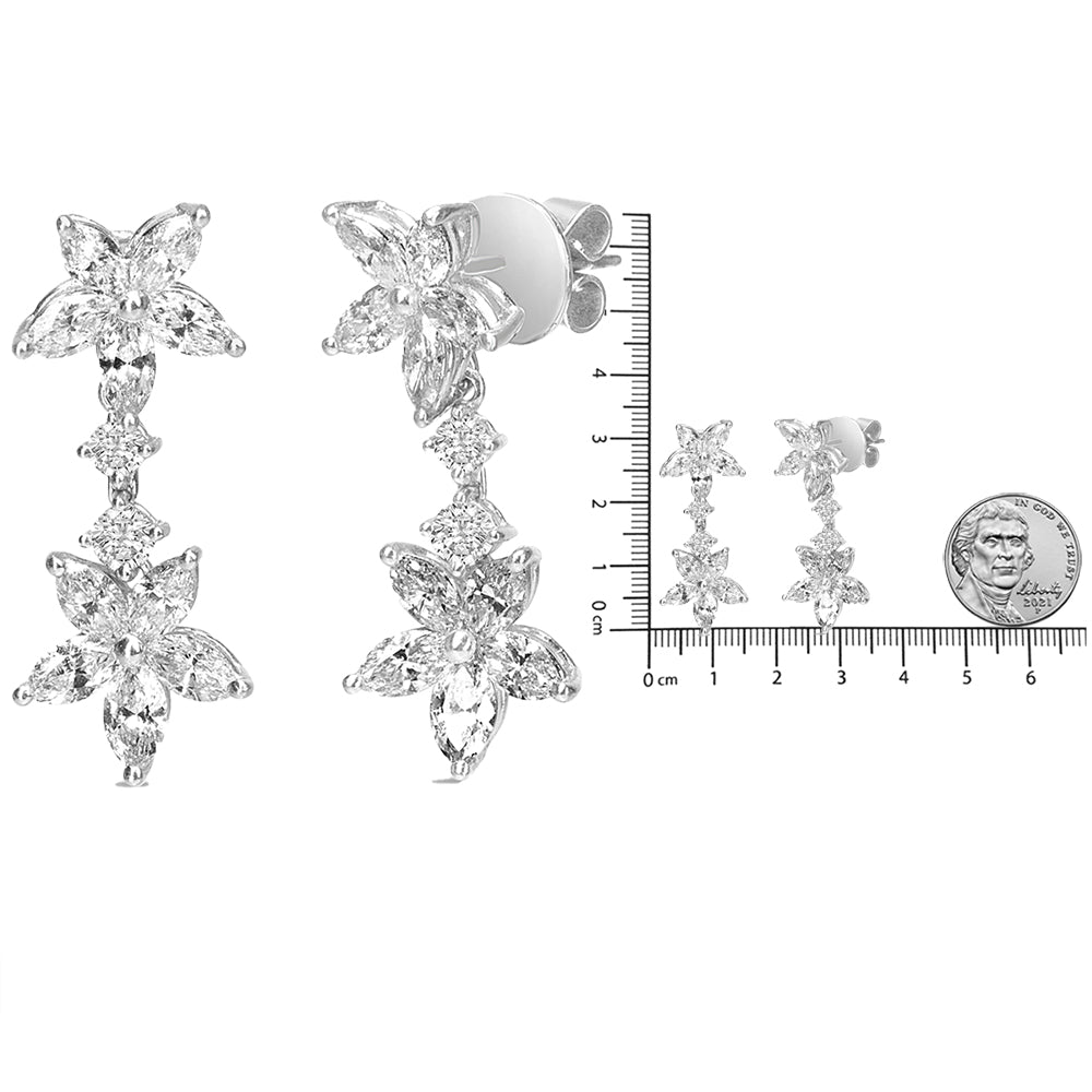 White metal dangling earrings with floral design composed of marquise and round white gemstones, shown from front and side angles, placed next to a ruler and coin for size reference.