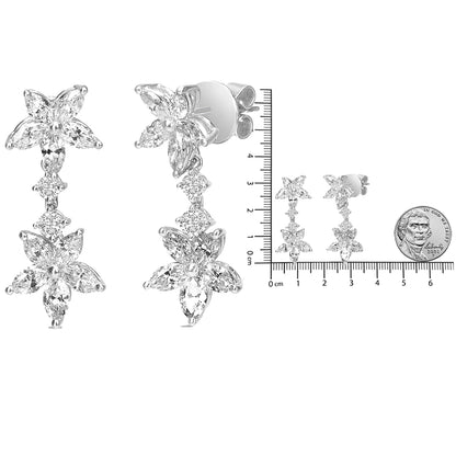 White metal dangling earrings with floral design composed of marquise and round white gemstones, shown from front and side angles, placed next to a ruler and coin for size reference.