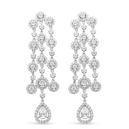 Front view of a pair of white metal chandelier earrings featuring multiple round white gemstones in prong and pave settings and a pear-shaped white gemstone at the bottom.