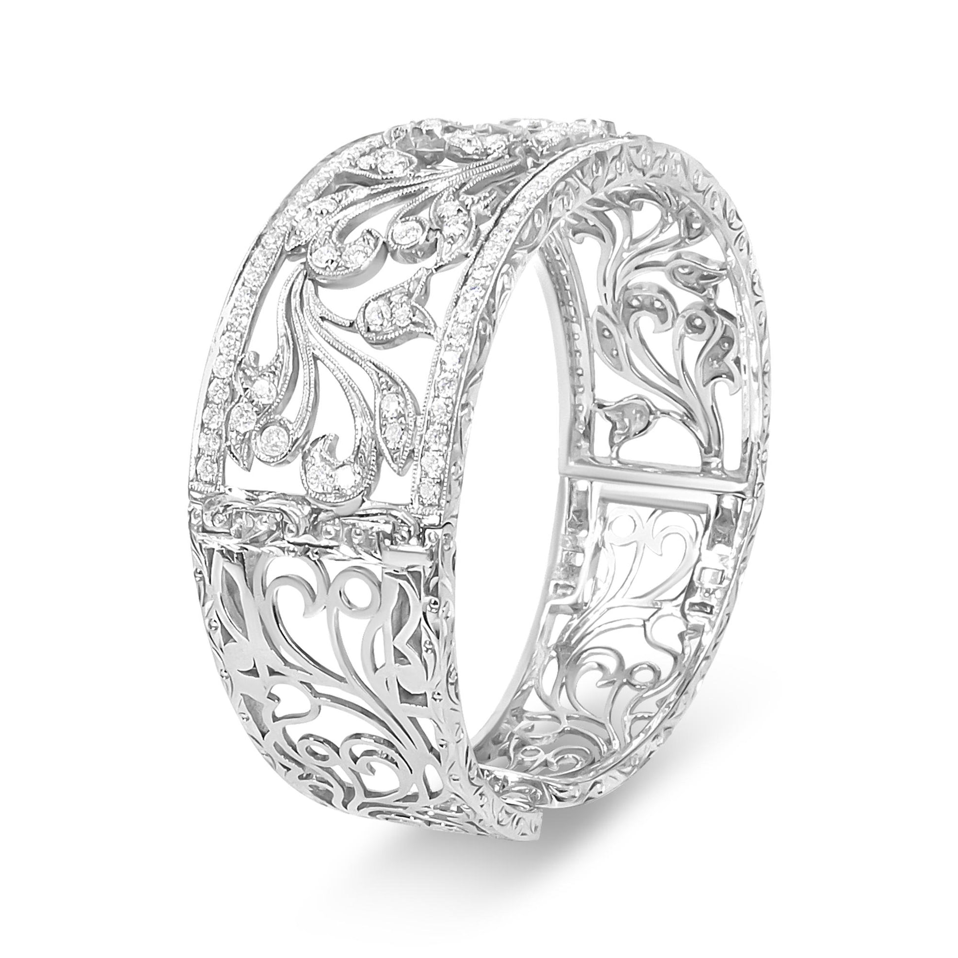White metal bracelet with intricate filigree design and pave set round white gemstones, shown at an angled view.