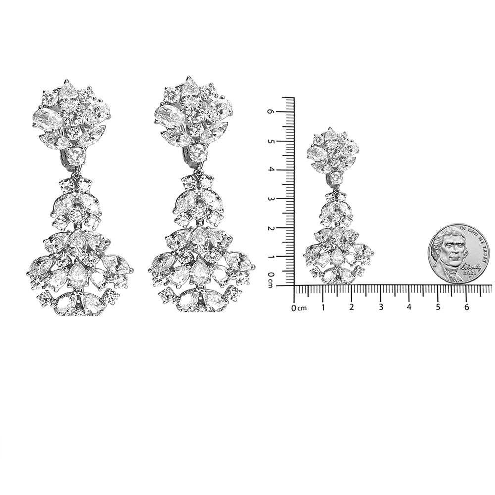 Pair of white metal drop earrings with multiple white gemstones in marquise, oval, round, and pear shapes, shown from the front angle; one earring is placed next to a ruler and coin for size reference.