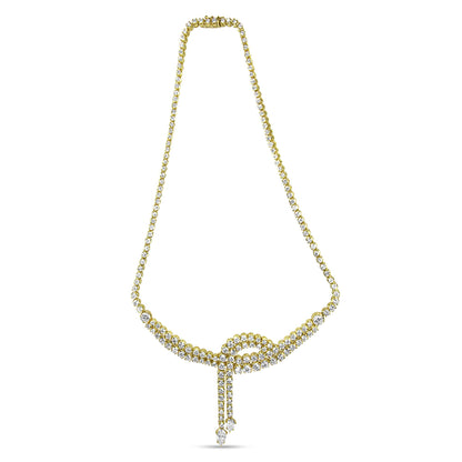 Front-facing shot of a yellow metal necklace with white round and pear-shaped gemstones arranged in a looped design with two dangling strands ending in pear-shaped gemstones.