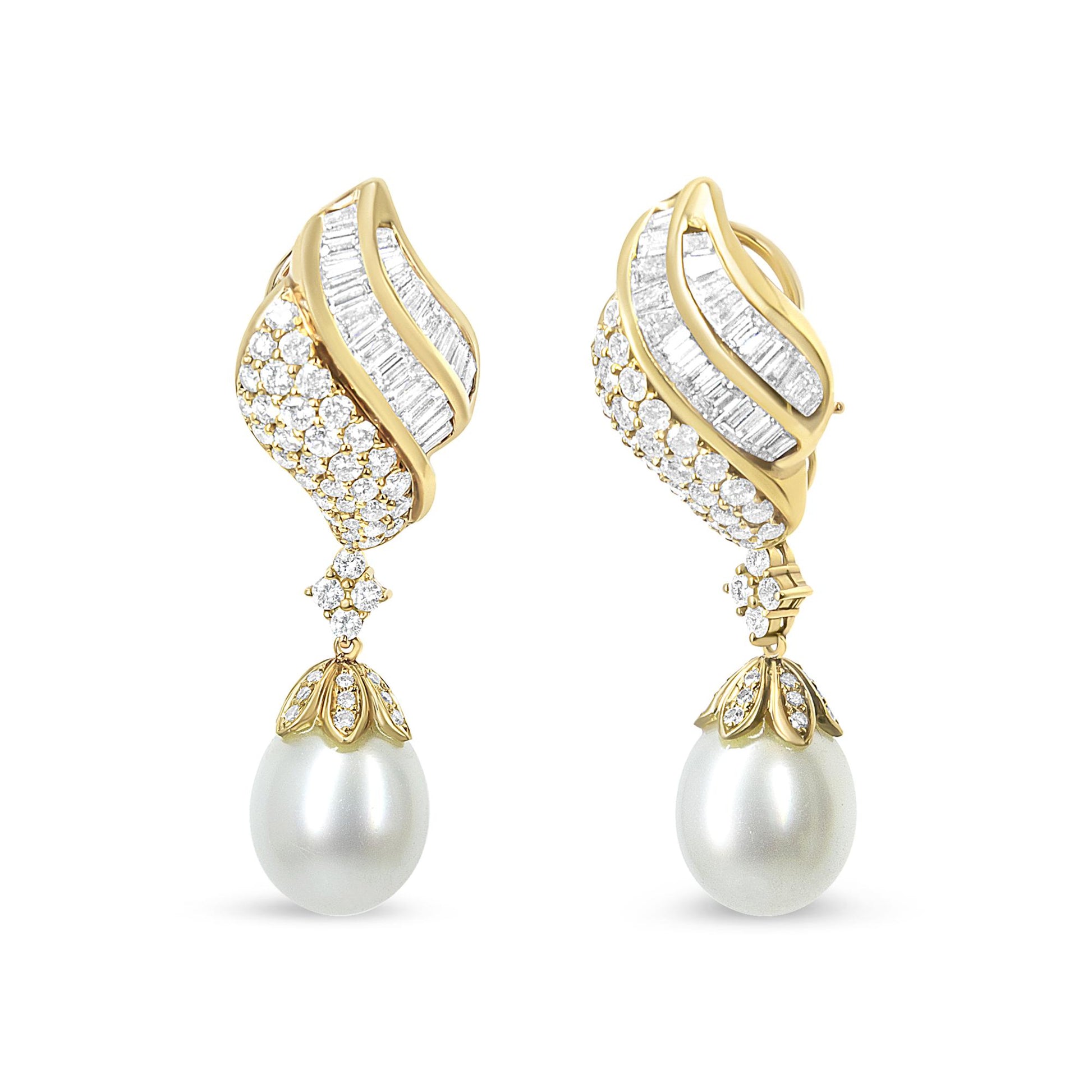 Front view of a pair of yellow metal earrings with curved designs featuring white baguette and round gemstones in channel and pave settings, each earring adorned with a large white pearl drop.