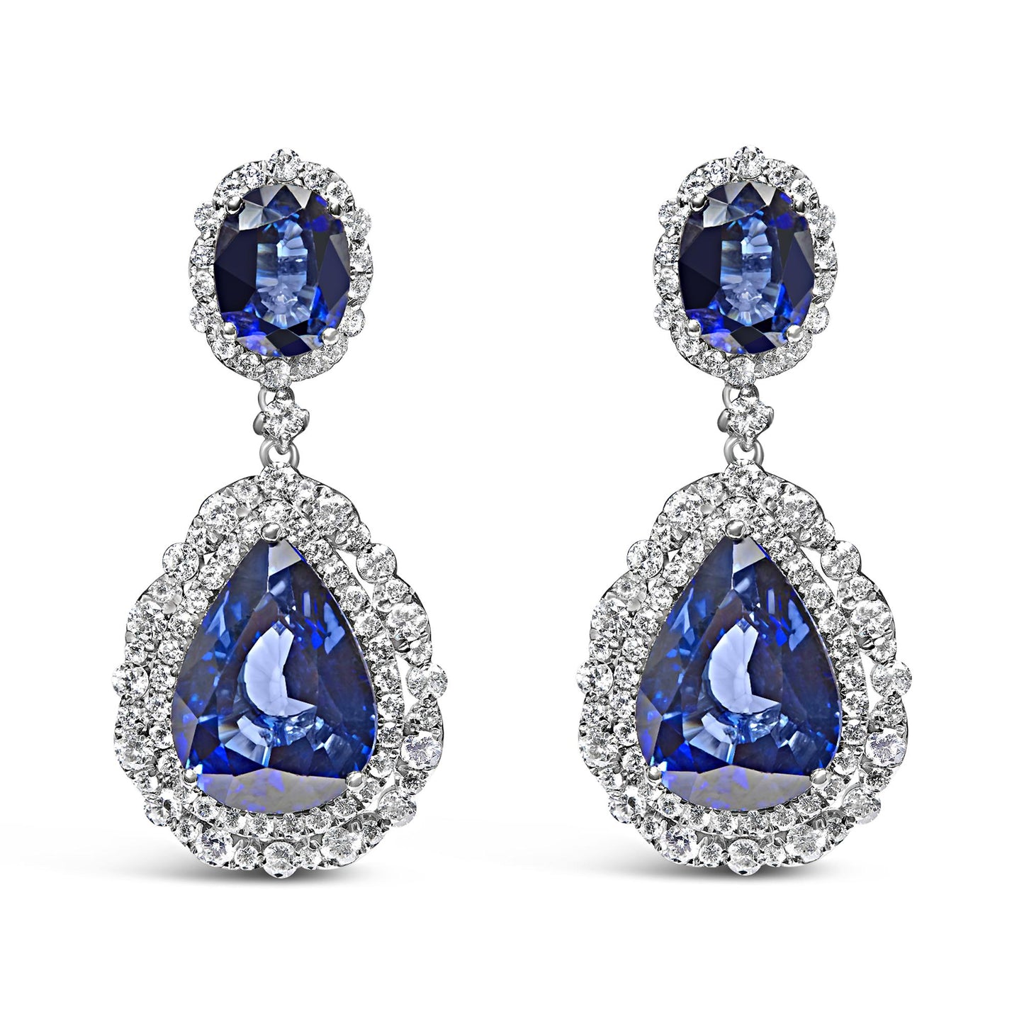 Front view of white metal drop earrings featuring oval and pear-shaped blue gemstones surrounded by white gemstones in prong settings.