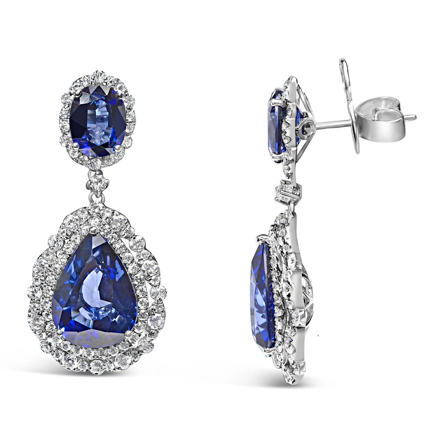 Front and side views of white metal drop earrings featuring oval and pear-shaped blue gemstones surrounded by multiple rows of small white gemstones in prong settings.