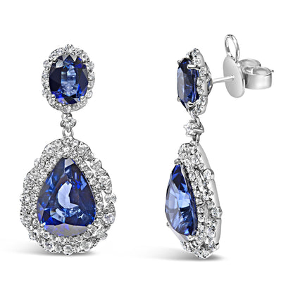 Pair of white metal drop earrings shown from front and side angles, featuring oval and pear-shaped blue gemstones surrounded by multiple round white gemstones in prong settings.