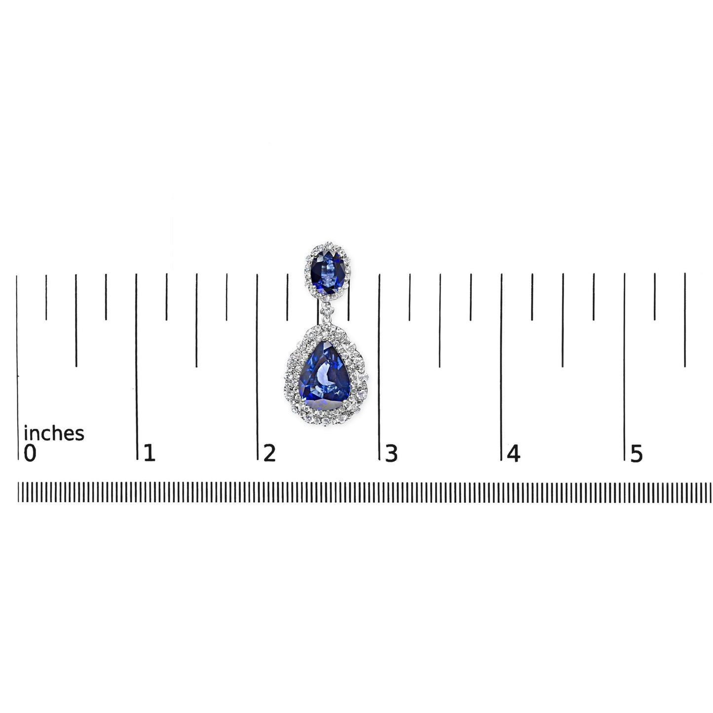 Single white metal earring with oval blue and pear-shaped blue gemstones surrounded by white gemstones, shown from the front on a ruler for size reference.