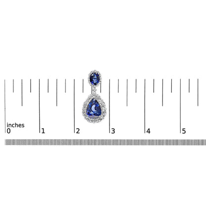 Single white metal earring with oval blue and pear-shaped blue gemstones surrounded by white gemstones, shown from the front on a ruler for size reference.