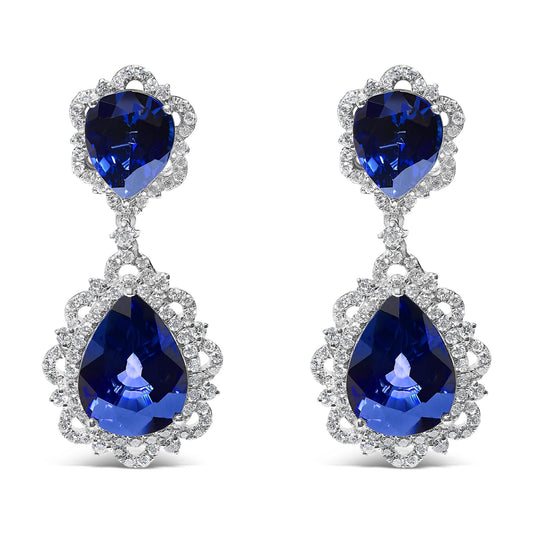 Pair of white metal drop earrings with pear-shaped blue gemstones surrounded by multiple small round white gemstones, shown in a front-facing view on a white background.