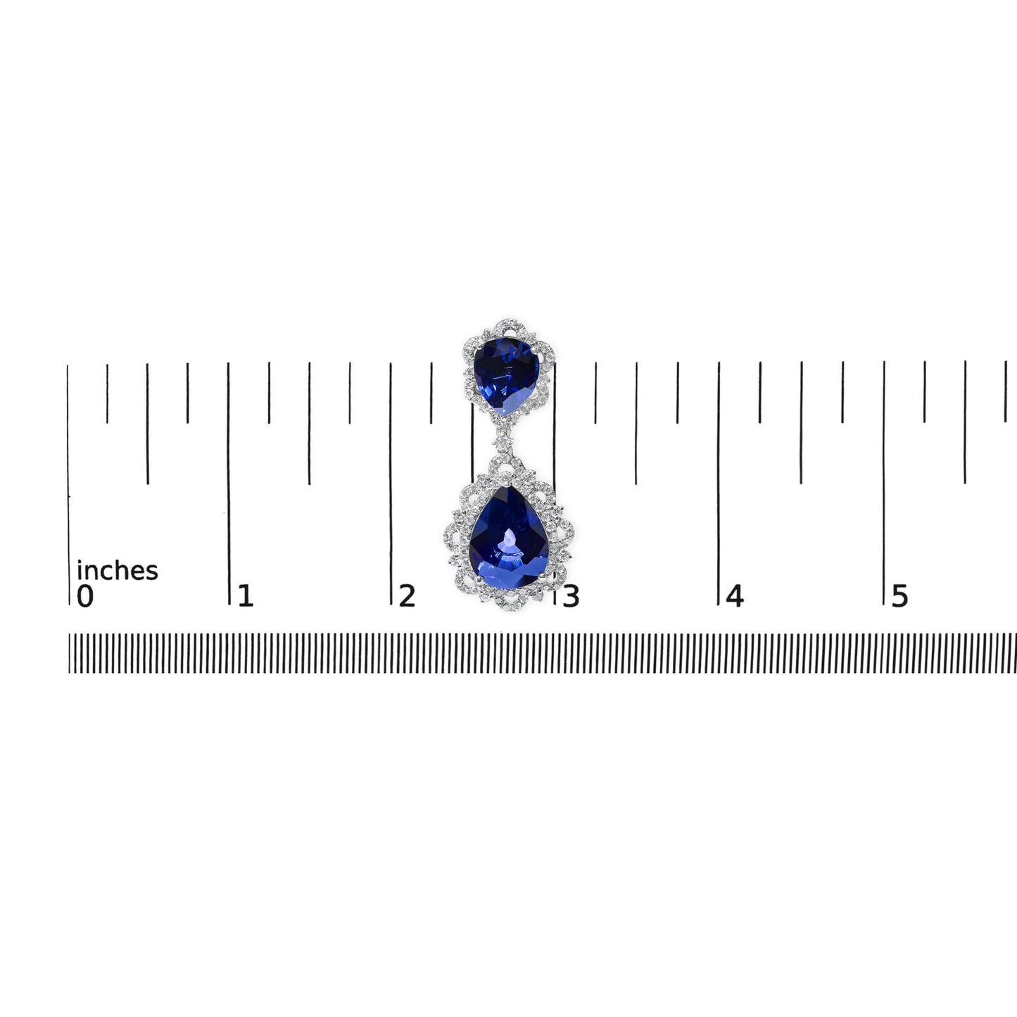 Single white metal earring with two pear-shaped blue gemstones surrounded by white gemstones, shown from above on a ruler for size reference.