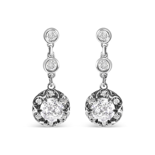 Front view of white metal drop earrings featuring two round prong-set white gemstones at the top and middle, followed by a larger round cluster of prong-set white gemstones surrounded by bezel-set white gemstones at the bottom.