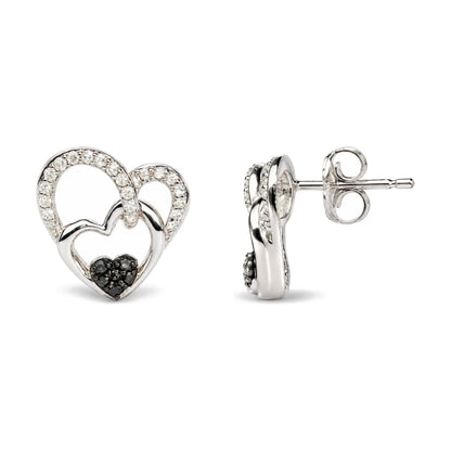 Close-up front and side view of white metal heart-shaped stud earrings, detailed with white and black round gemstones in prong settings.