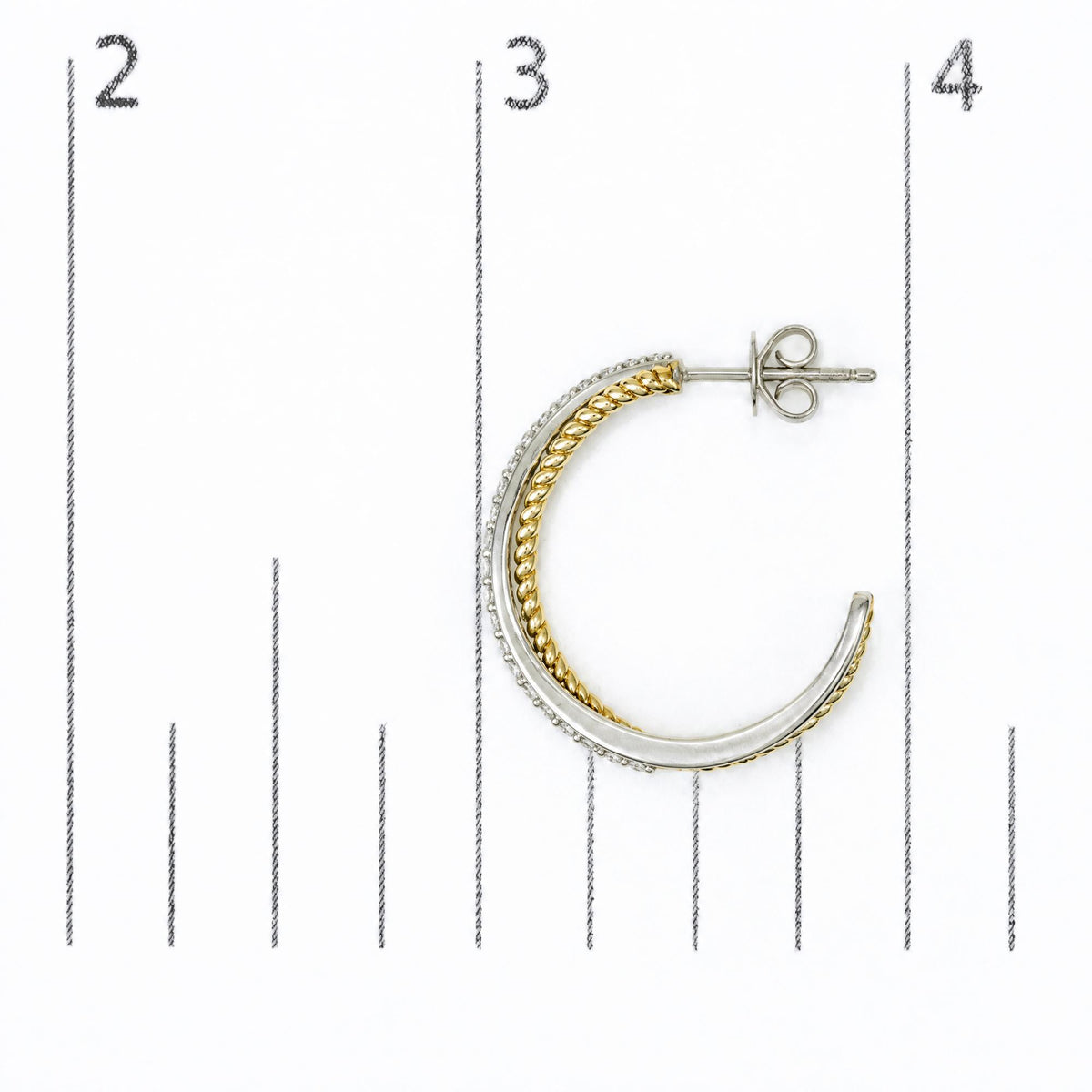 Close-up top view of a half hoop earring shown on a scale, featuring intertwined yellow and white metal bands with small round white gemstones set along one edge.