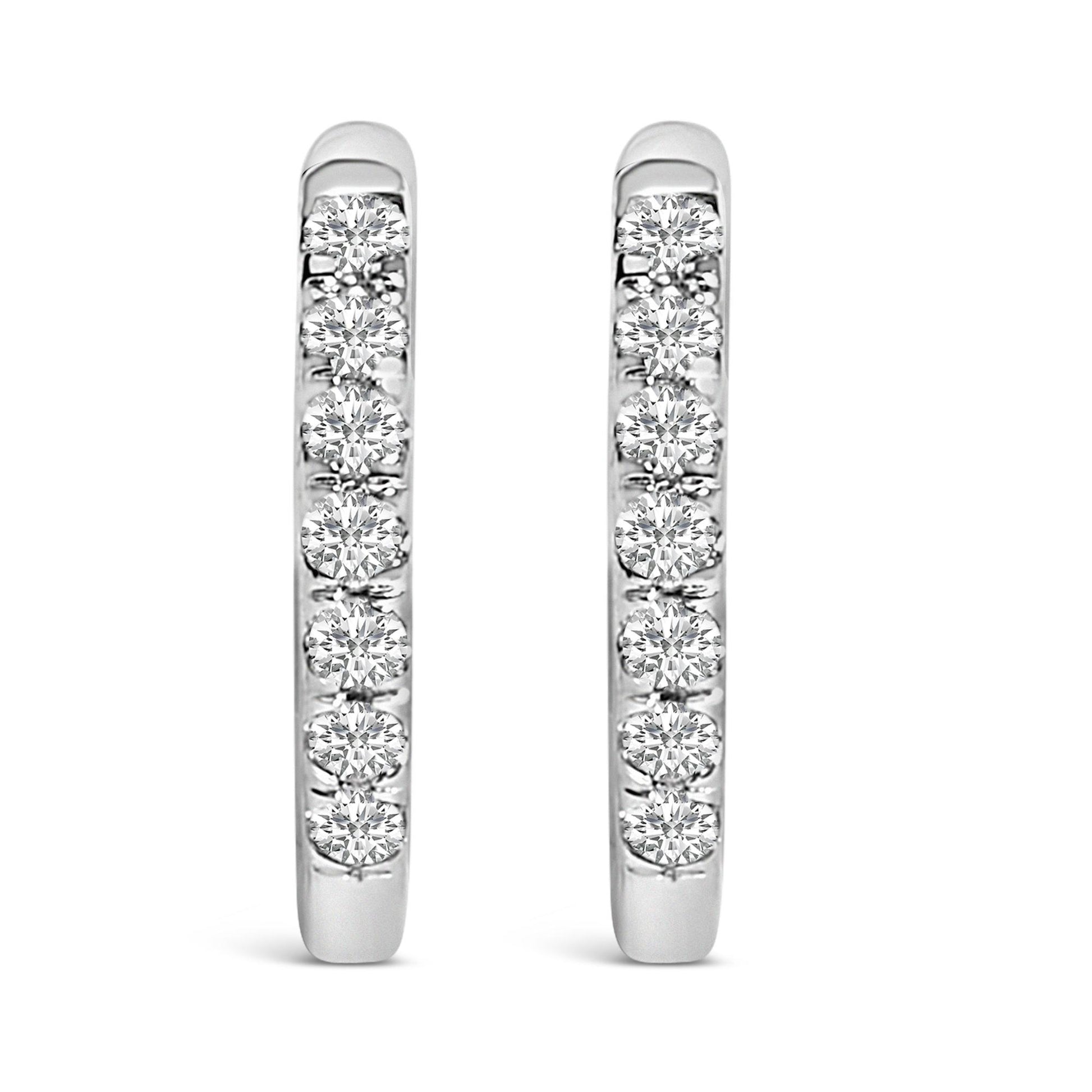 Front view of a pair of white metal hoop earrings each set with multiple round white gemstones in shared prong settings.