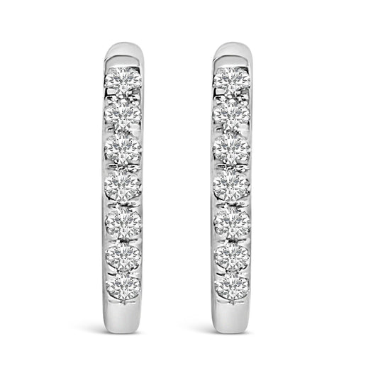 Front view of a pair of white metal hoop earrings each set with multiple round white gemstones in shared prong settings.