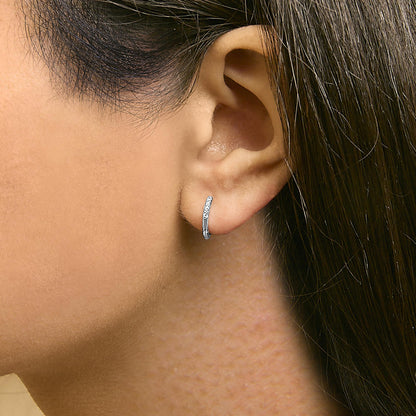 Close-up side view of a white metal hoop earring adorned with round white gemstones in a shared prong setting, shown worn on a model's ear.