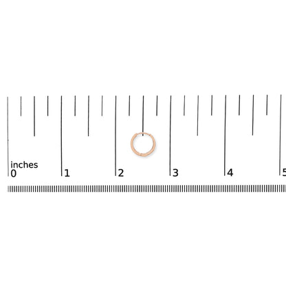 Rose-colored round hoop earring with white round gemstones in 4-prong settings along one side, shown on a ruler scale, front-facing angle.