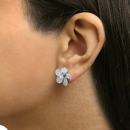 Close-up side view of a model wearing a white flower-shaped earring with a round white gemstone in the center.