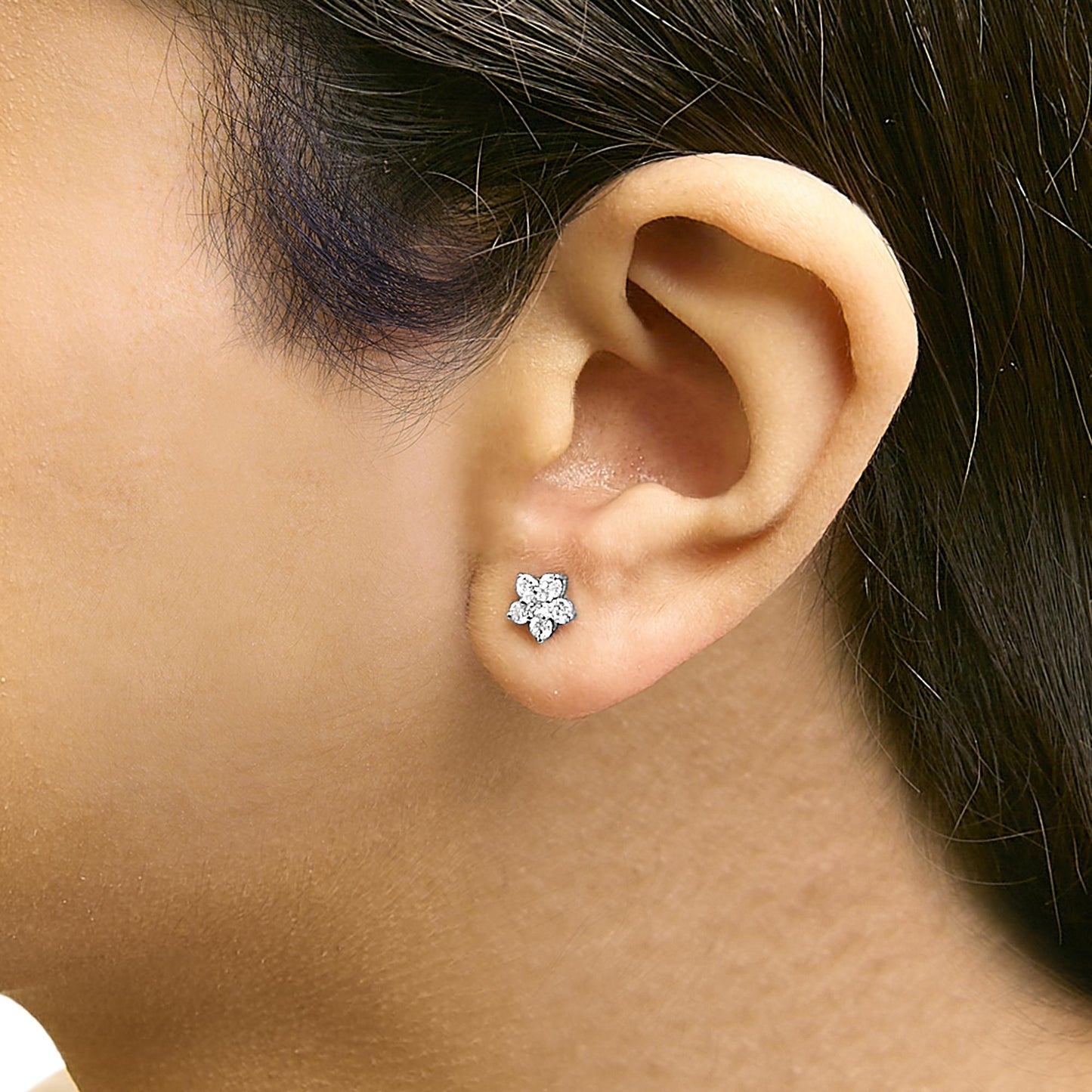 Close-up side view of a model wearing a white metal stud earring designed with multiple round white gemstones in a prong setting.