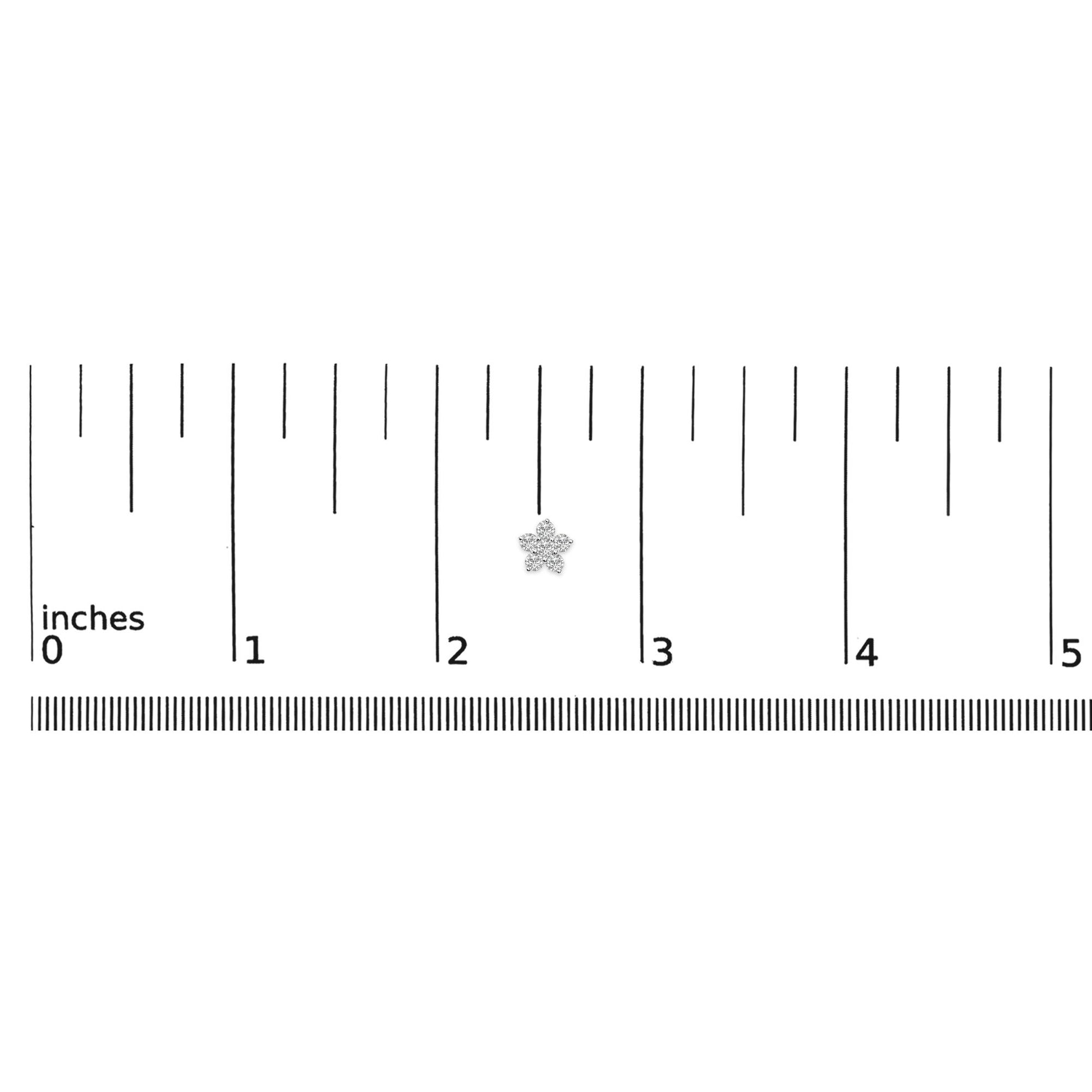 White metal earrings with round white gemstones in a prong setting arranged in a small flower shape, shown flat on a ruler scale, top-down angle.