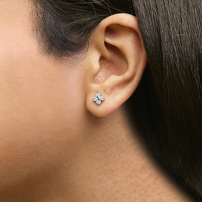White metal earrings with four round white gemstones in a prong setting, shown worn on a model from a side angle.