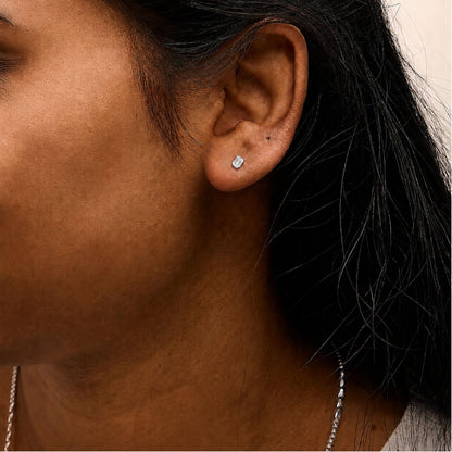 Close-up side view of a model wearing white earrings with emerald-shaped white gemstones set in 4-prong settings.