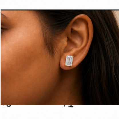 Close-up side view of a model wearing a yellow metal earring featuring a white gemstone in an emerald shape with a four-prong setting.