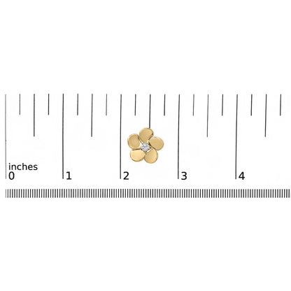Close-up top view of a small yellow metal flower-shaped earring with a single white round gemstone in the center, shown placed on a ruler scale.