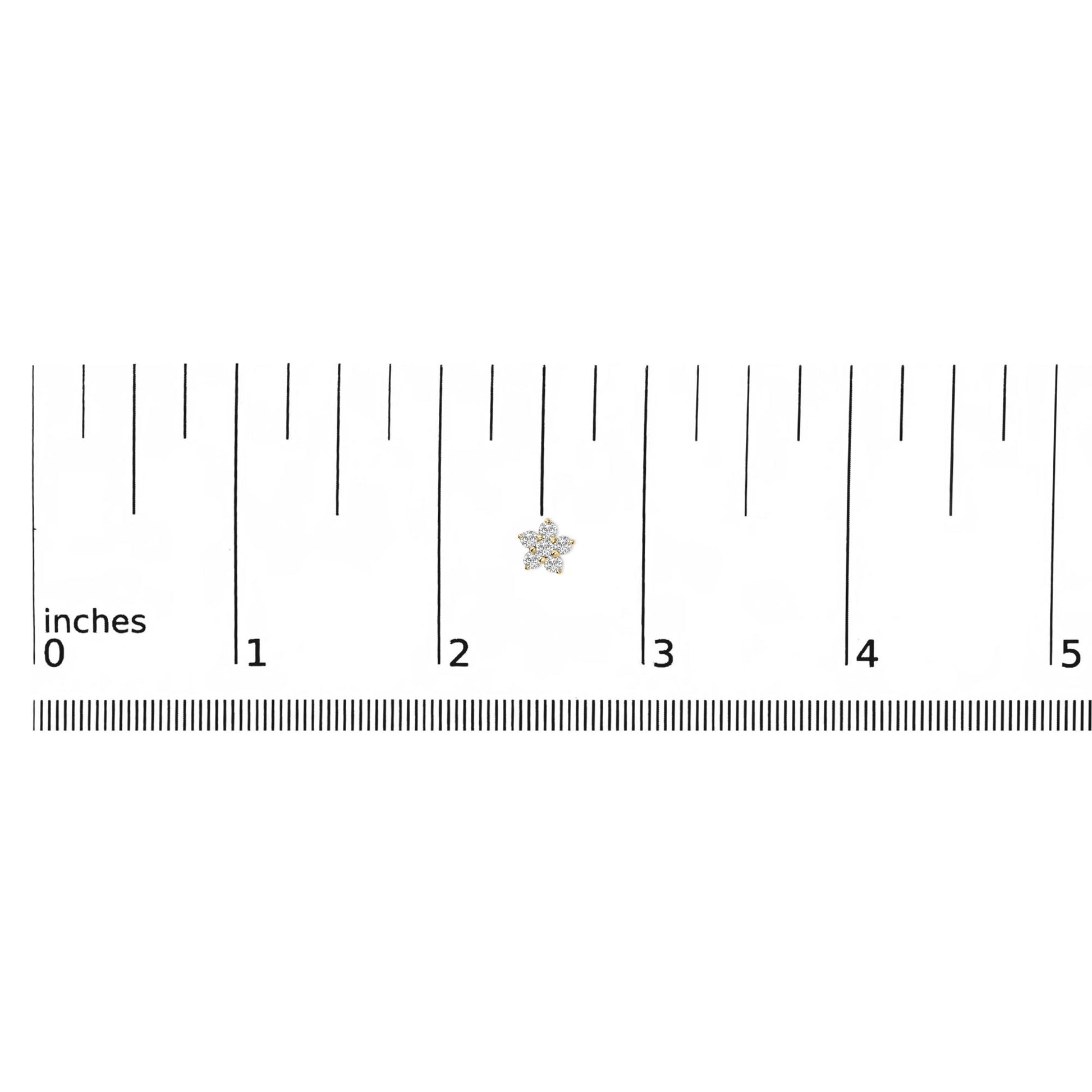 Yellow metal earring with round white gemstones in prong settings forming a floral shape, shown on a ruler scale from a top-down angle.