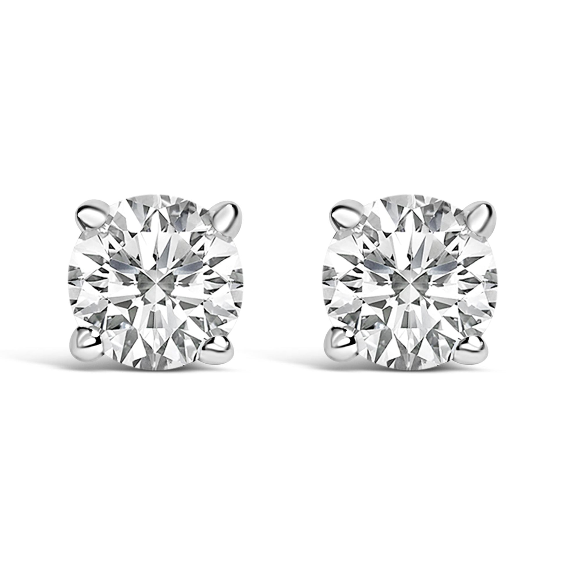 Close-up front view of a pair of white metal stud earrings, each featuring a round white gemstone in a four-prong setting.