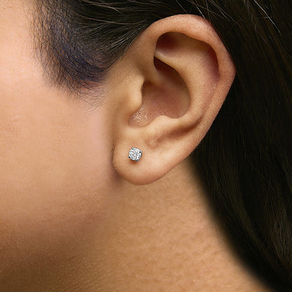 Close-up side view of a model wearing a pair of white metal stud earrings featuring round white gemstones in a four-prong setting.