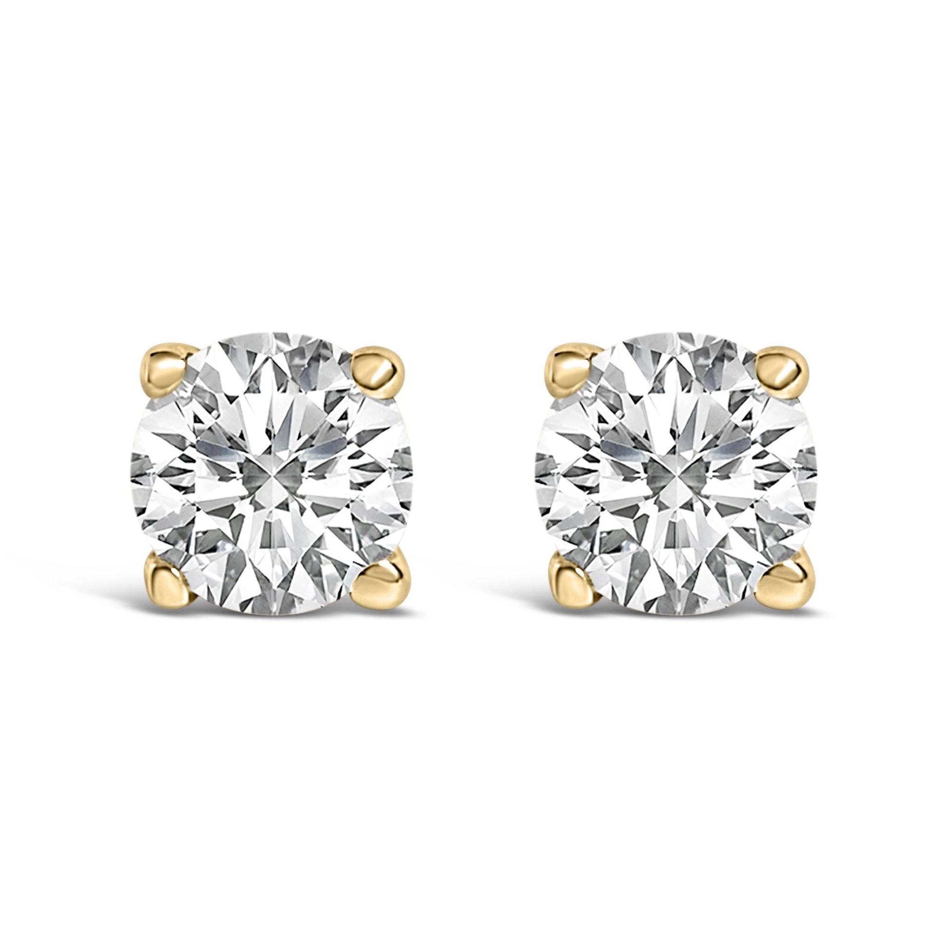 Front view of a pair of yellow metal stud earrings each set with a round white gemstone in a four-prong setting, shown on a white background.