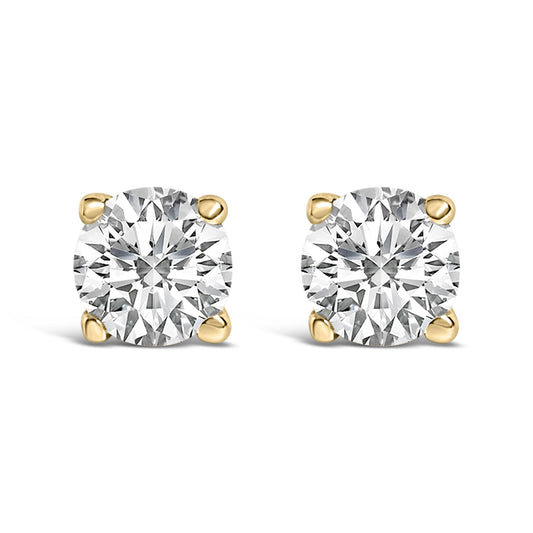 Front view of a pair of yellow metal stud earrings each set with a round white gemstone in a four-prong setting, shown on a white background.