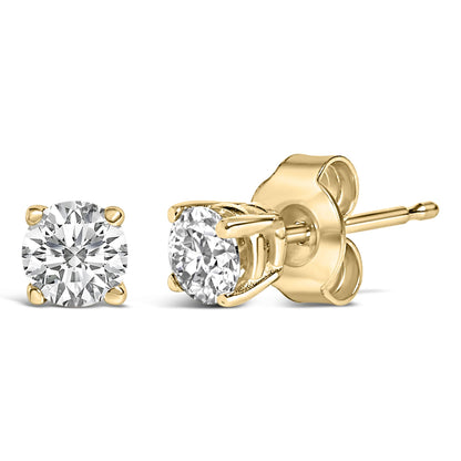 Close-up front and side view of a pair of yellow metal stud earrings with round white gemstones in four-prong settings.